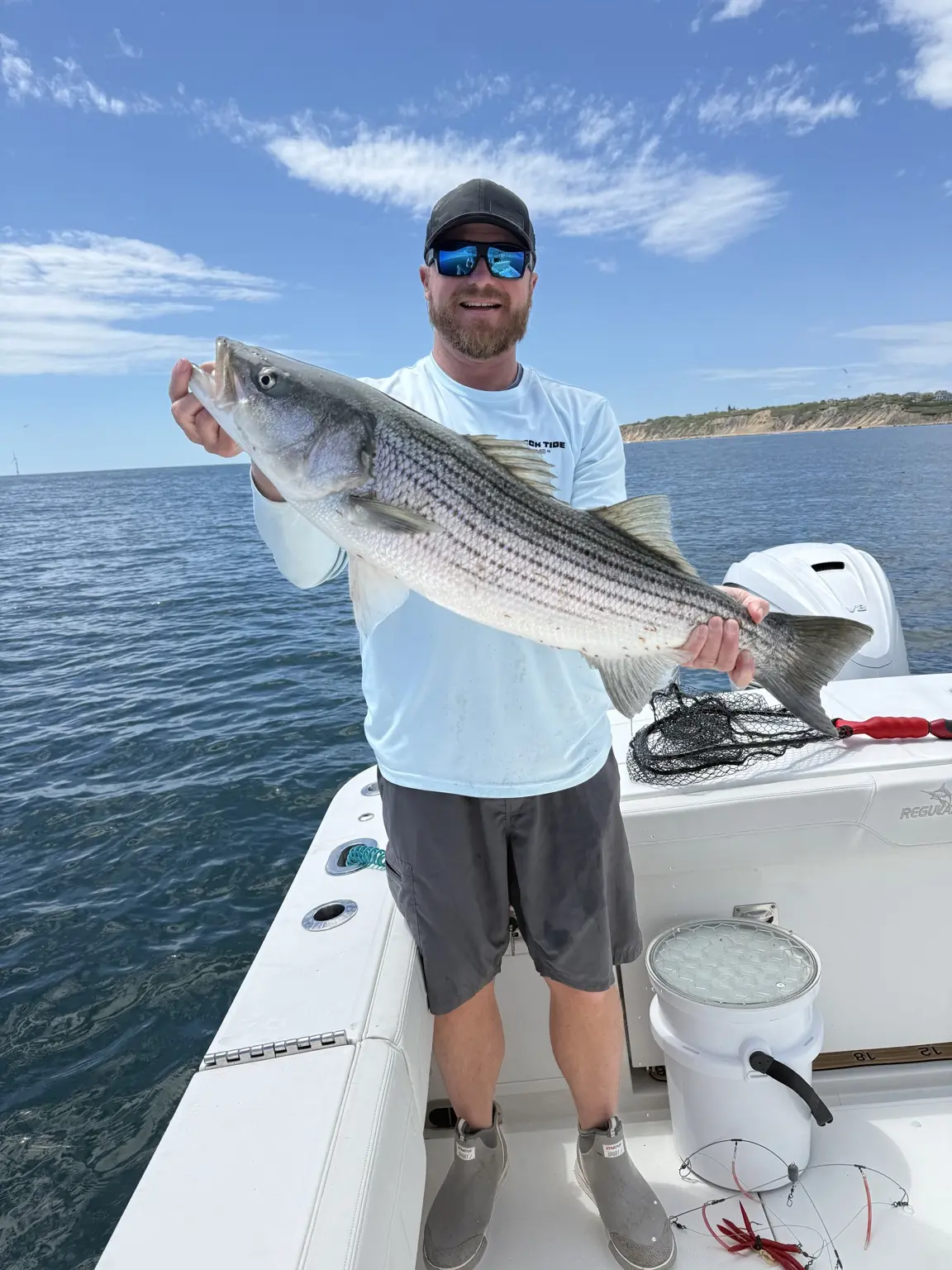 Angler holding a striped bass near the Rhode Island coast